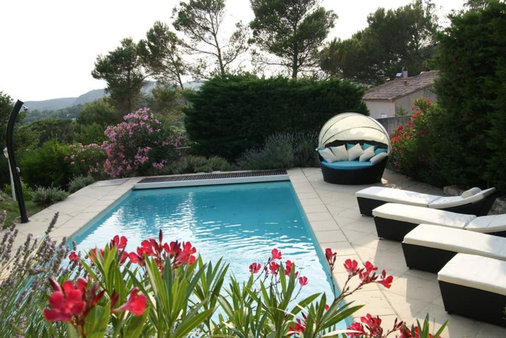 einen Pool in einem Garten mit einer Bank und Blumen in der Unterkunft Elegante villa de 180m3 avec la superbe vue in Connaux