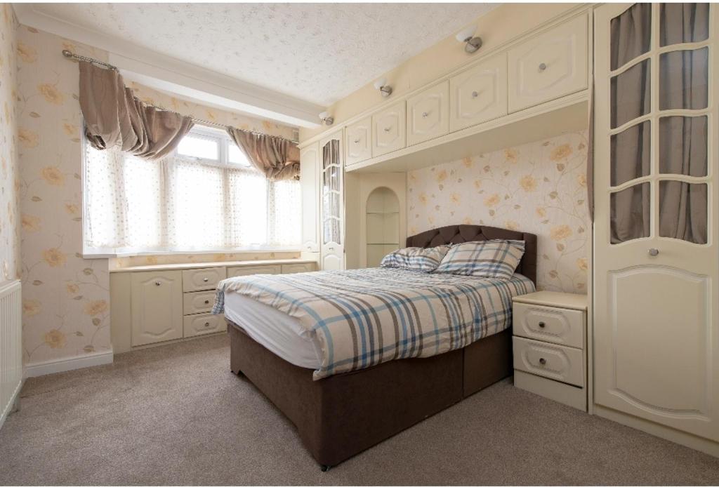 a bedroom with a bed and a window at Spacious Bungalow in Romford with parking in Romford