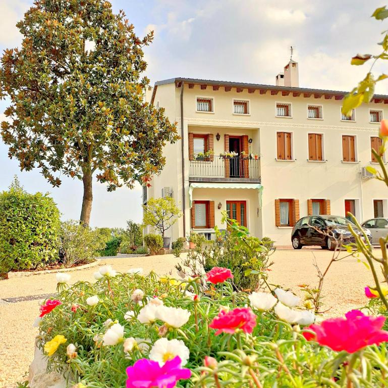 un bâtiment avec des fleurs devant lui dans l'établissement Le Vigne di Annalisa Sweet Relax Rooms in Unesco Prosecco D.o.c.g., à Farra di Soligo