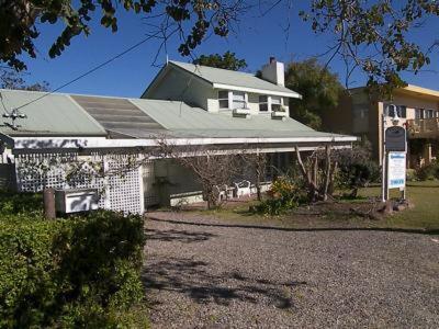 a white house with a sign in front of it at Casablanca Enchanted Cottage in Nelson Bay