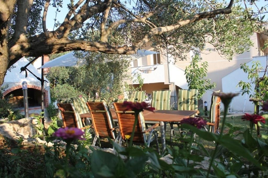 a wooden table and chairs in a yard with flowers at Apartments Ante - 50m from the sea in Posedarje