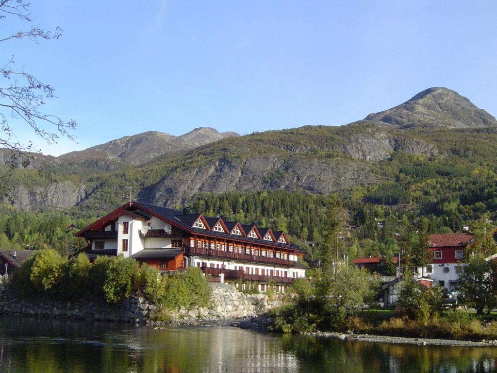 a building next to a river with mountains in the background at Fanitullen Hotel in Hemsedal