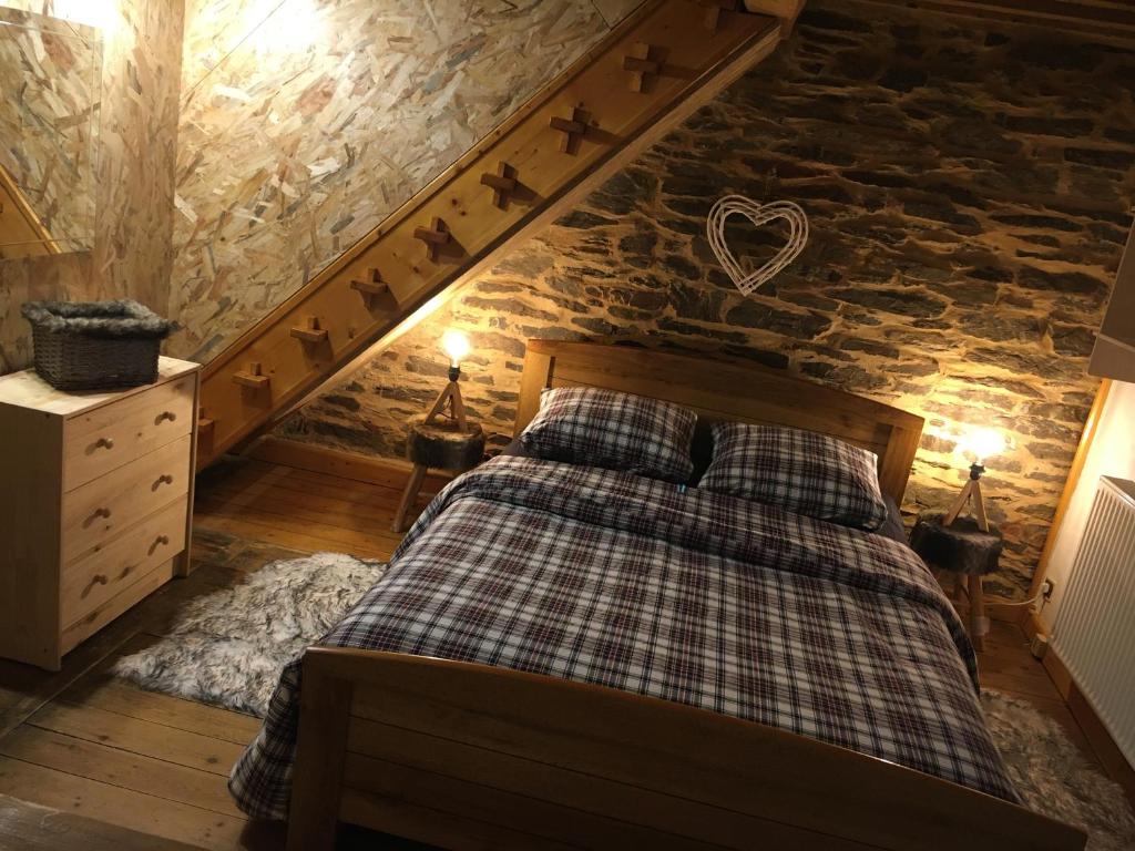 a bedroom with a bed and a stone wall at La Pénates in Château-Regnault-Bogny