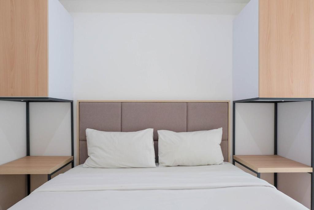 a bedroom with a bed with two side tables at Best Price 2BR Apartment @ Midtown Residence By Travelio in Tangerang