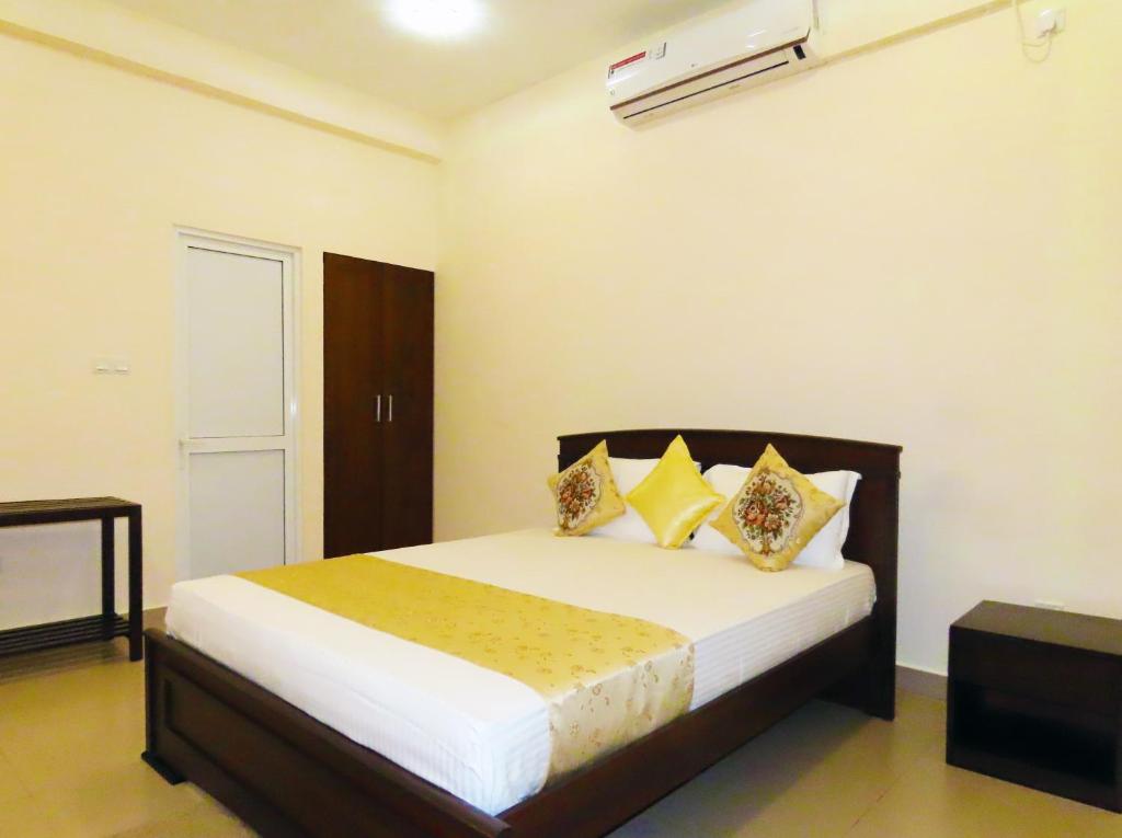 a bedroom with a bed with white sheets and yellow pillows at VIVAS Residencies Luxury Apartments in Colombo