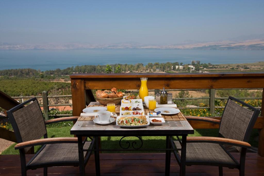 a table with food on a deck with a view of the water at Ramot Resort Hotel in Moshav Ramot