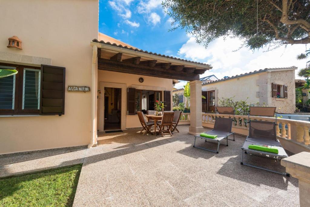 a patio with a table and chairs next to a house at Alga Marina in Son Serra de Marina