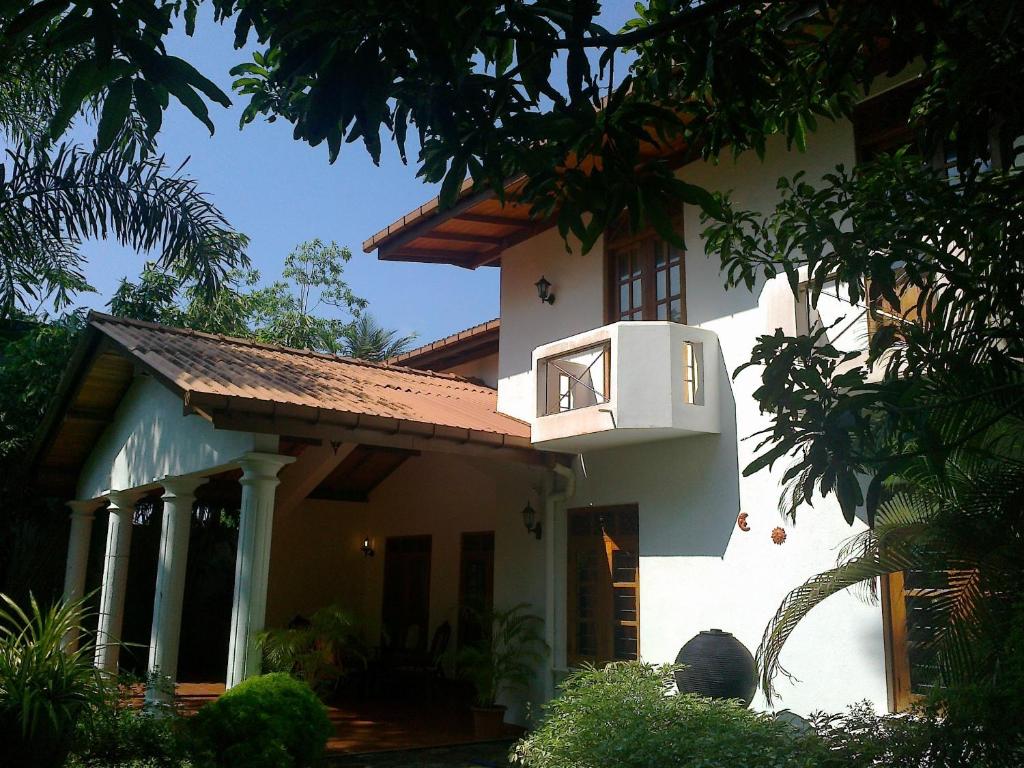 Una casa blanca con un balcón en el lateral. en Rohan Villa, en Hikkaduwa
