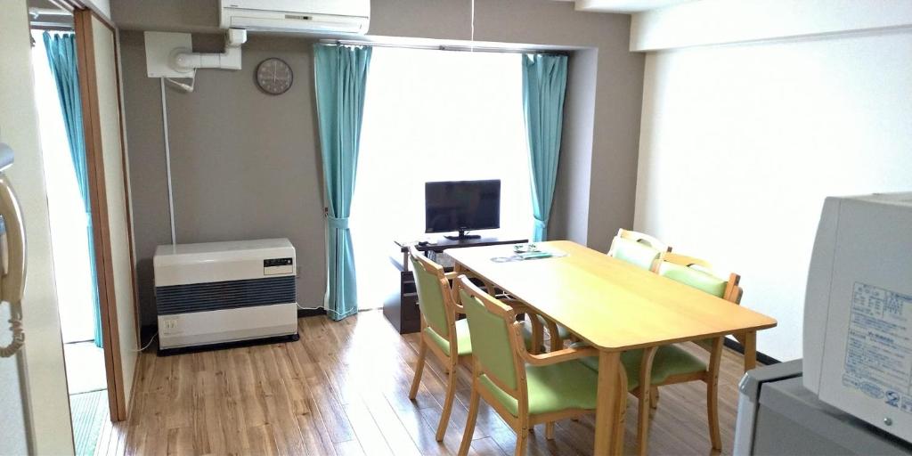 a dining room with a table and chairs and a television at 札幌市中心部大通公園まで徒歩十分観光移動に便利なロケーションh702 in Sapporo