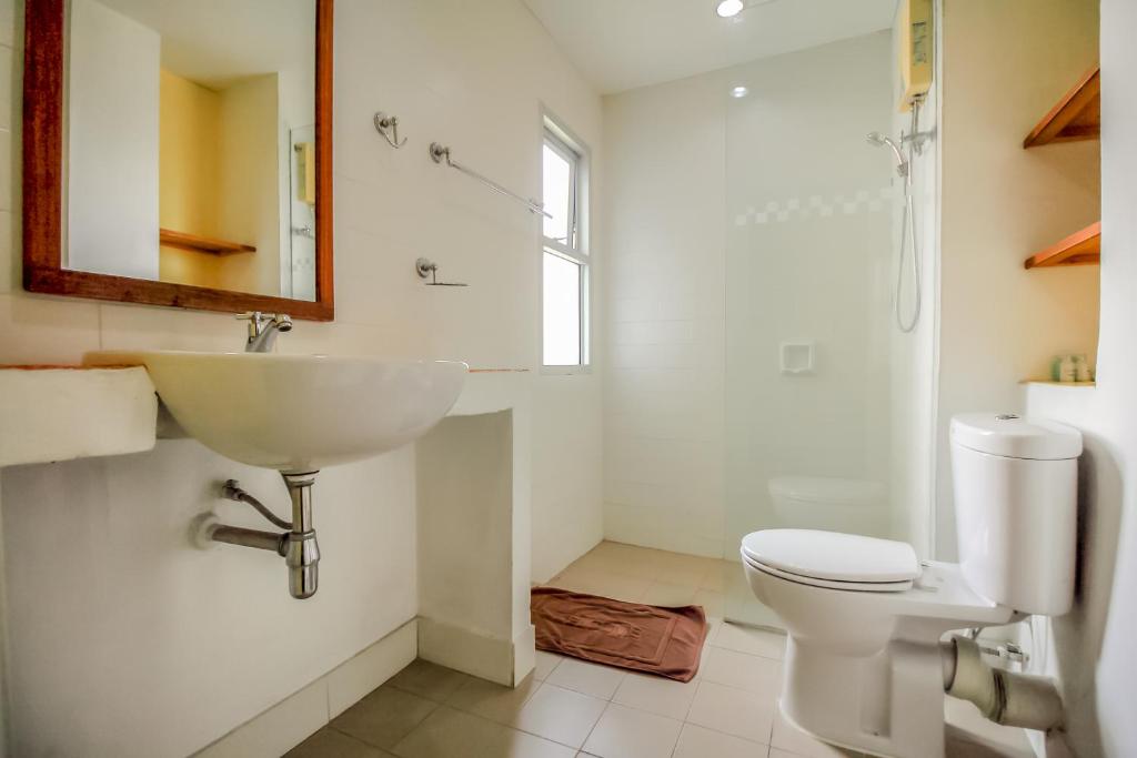 A bright tiled bathroom includes a vessel sink, toilet and open shower area.