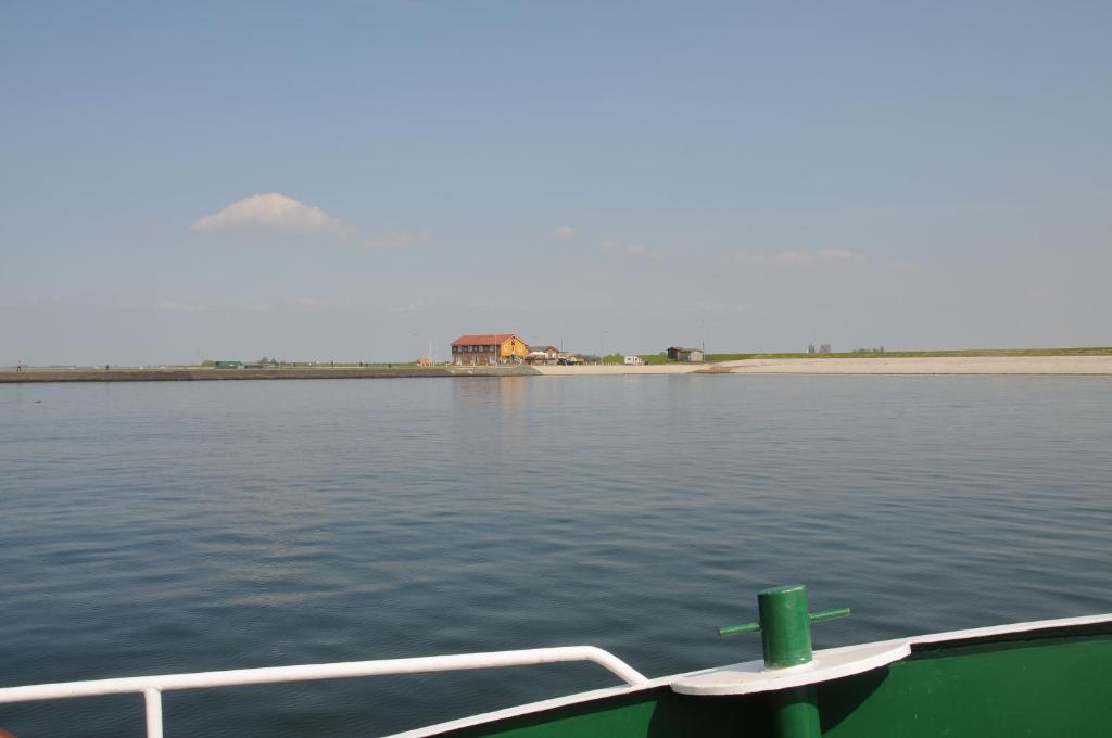 a boat on the water with a house in the distance at Residentie Oosterschelde in Sint Philipsland
