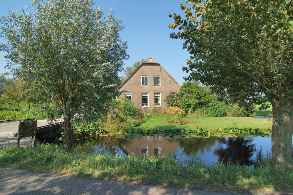 Bed & Breakfast De Ruige Weide في Oudewater: منزل وبركة امام منزل