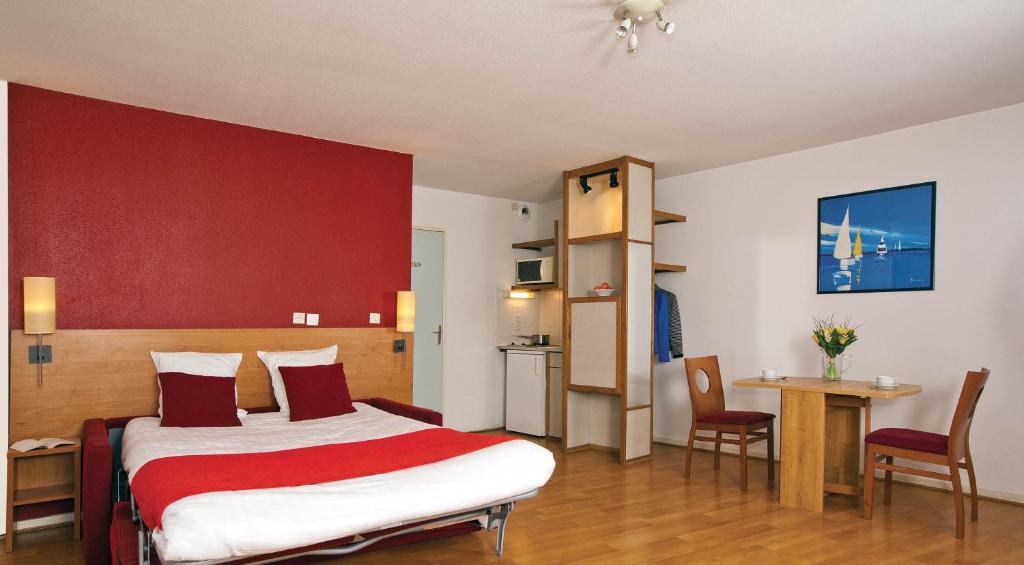 Habitación de hotel con cama con pared roja en Séjours & Affaires Lyon Saxe-Gambetta, en Lyon