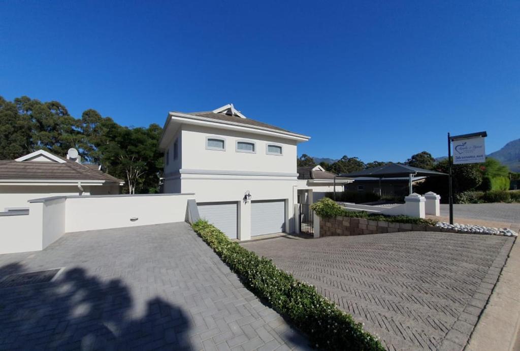 a white house with a fence and a driveway at Apple And Spice Guest House in George