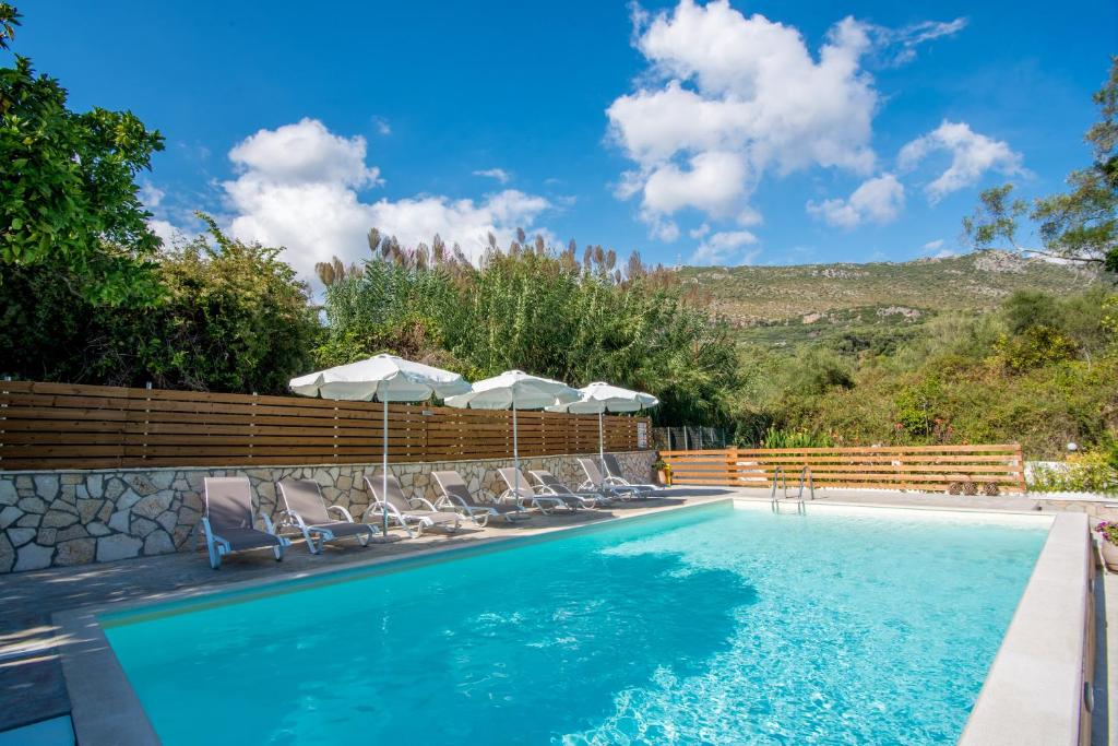 a swimming pool with lounge chairs and umbrellas at Dallas Valtos Studios in Parga