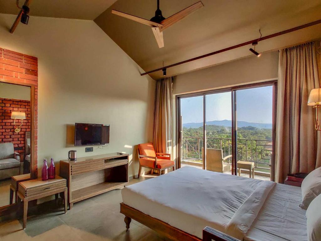Habitación de hotel con cama y ventana grande en Advait Resort Kshetra Mahabaleshwar en Mahabaleshwar