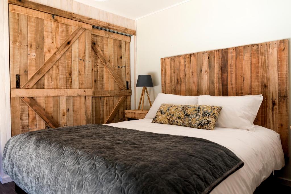 1 dormitorio con 1 cama grande y pared de madera en Cabañas Los Huemules en Malalcahuello