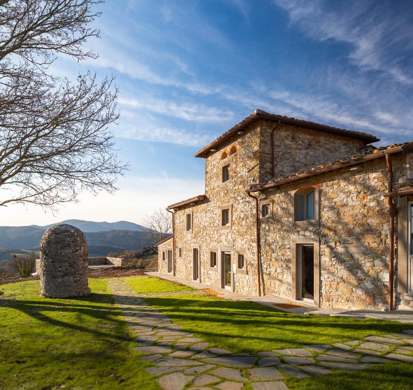 Vaglia的住宿－Agri Resort & SPA Le Colline del Paradiso，一座位于草地山上的古老石头建筑