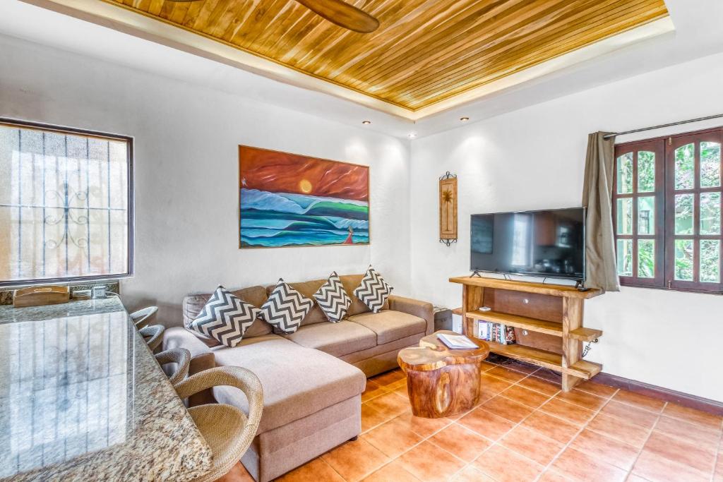 ein Wohnzimmer mit einem Sofa und einem TV in der Unterkunft Los Suenos II #17 in Tamarindo