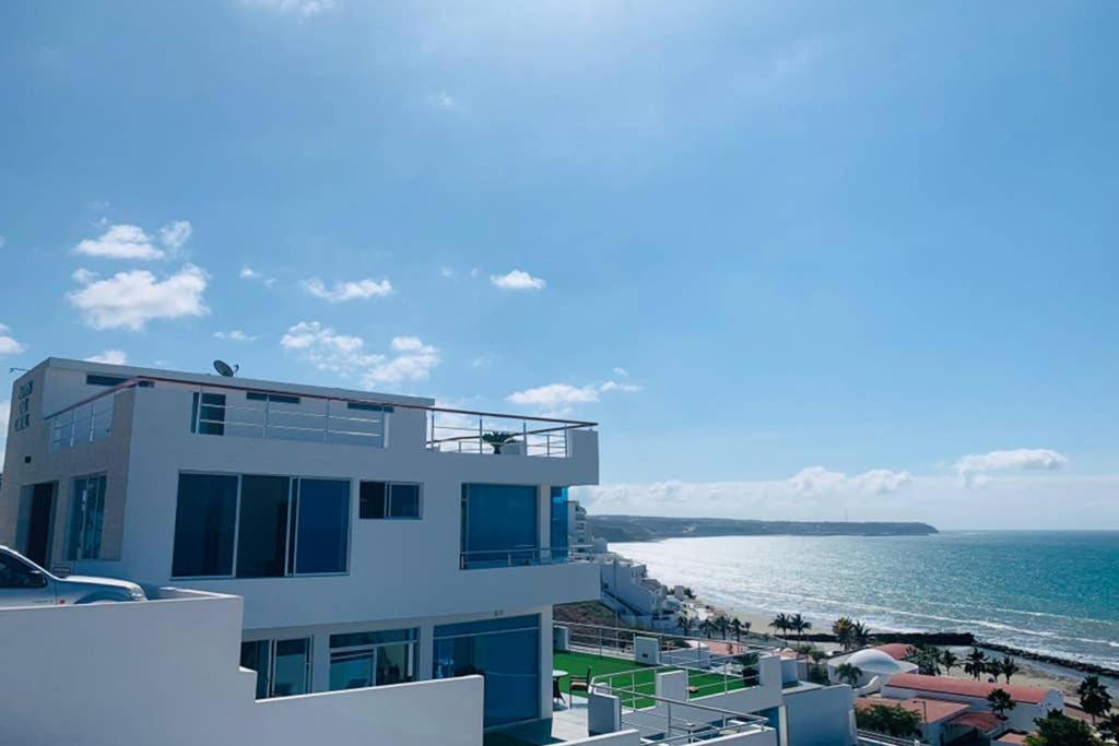 ein weißes Gebäude neben einem Strand mit Meer in der Unterkunft Exclusivo Penthouse frente al mar con acceso a la playa - Club Privado en Manta in Manta