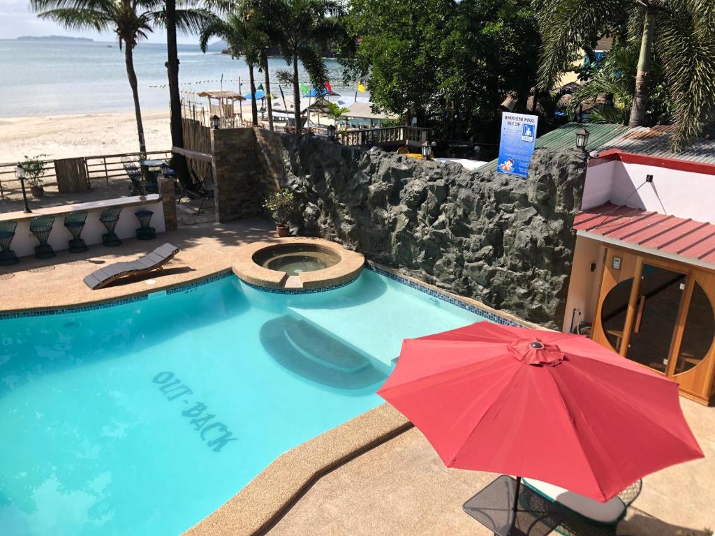 ein roter Regenschirm neben einem Pool mit Strand in der Unterkunft Out Back in Olongapo