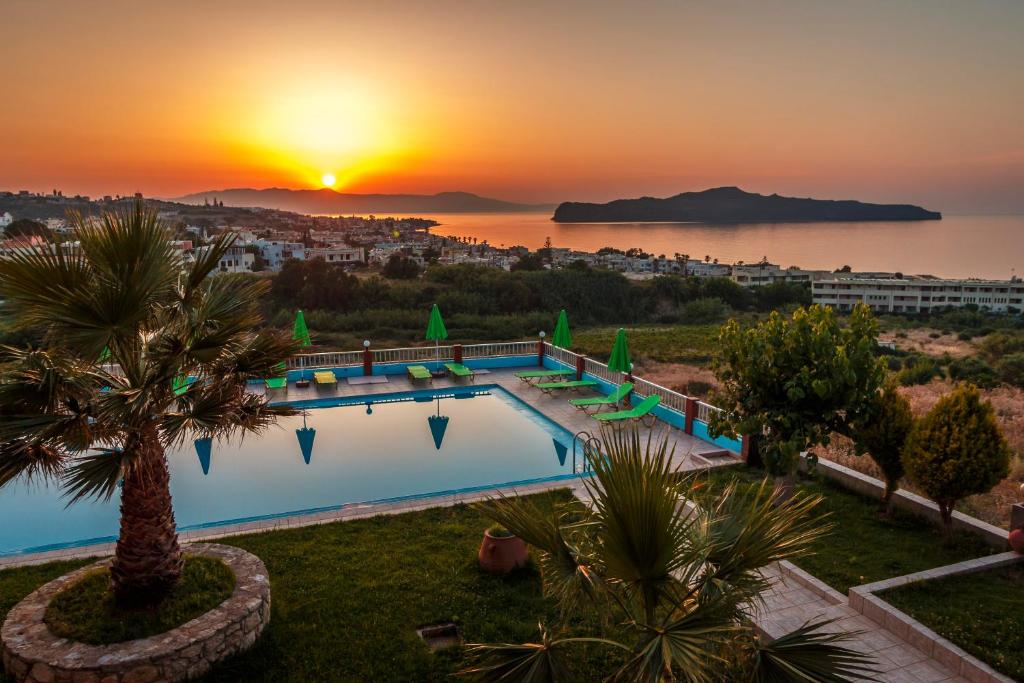 a swimming pool with a sunset in the background at Eliros Studios in Stalos