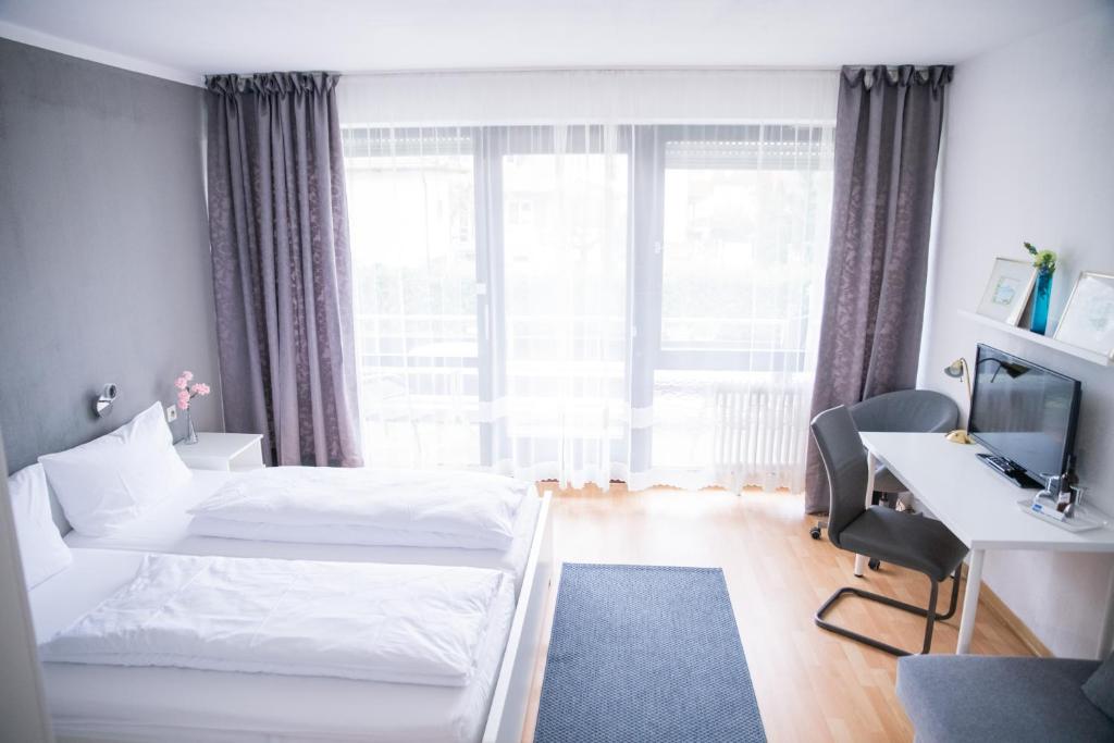 Habitación de hotel con 2 camas, escritorio y TV. en Römerhof en Bad Bellingen
