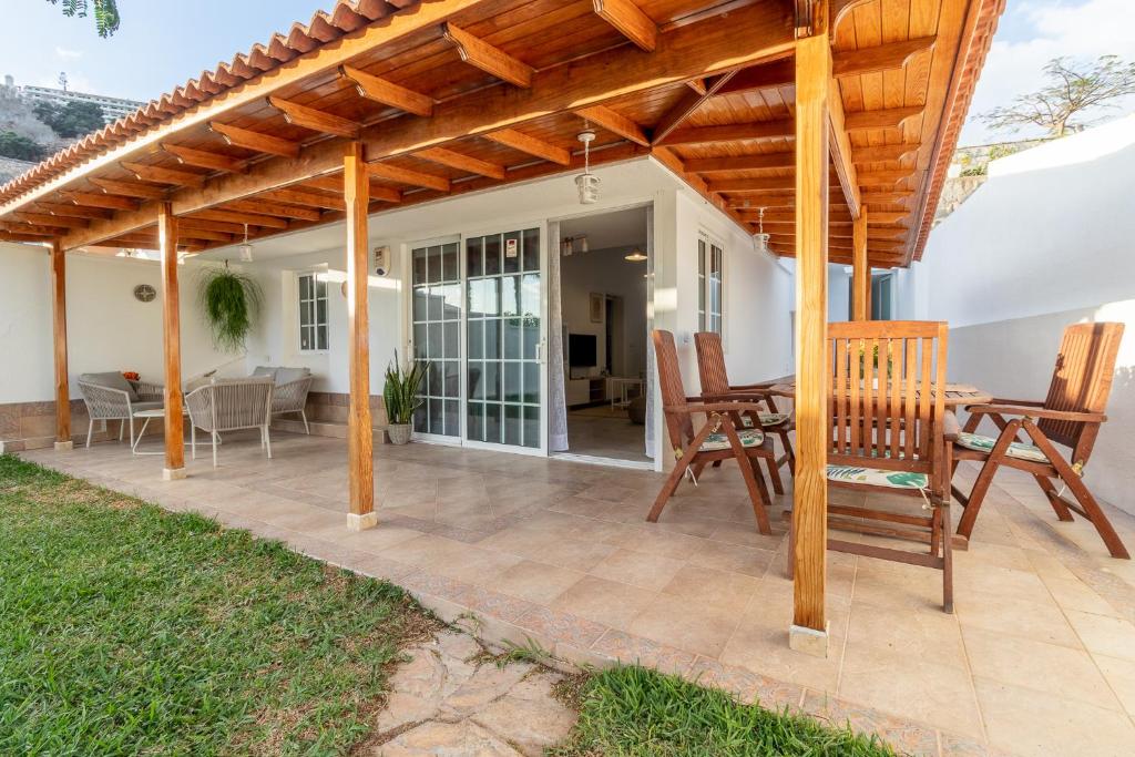 a patio with a wooden pergola and chairs at Flatguest Orinoco + Pool + Terrace + Garden in Mogán