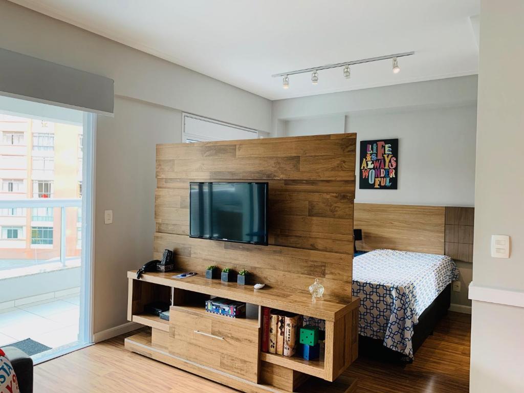 Schlafzimmer mit einer großen Holzwand und einem Flachbild-TV in der Unterkunft CS Apartamento a 200 metros da Paulista com AC in São Paulo