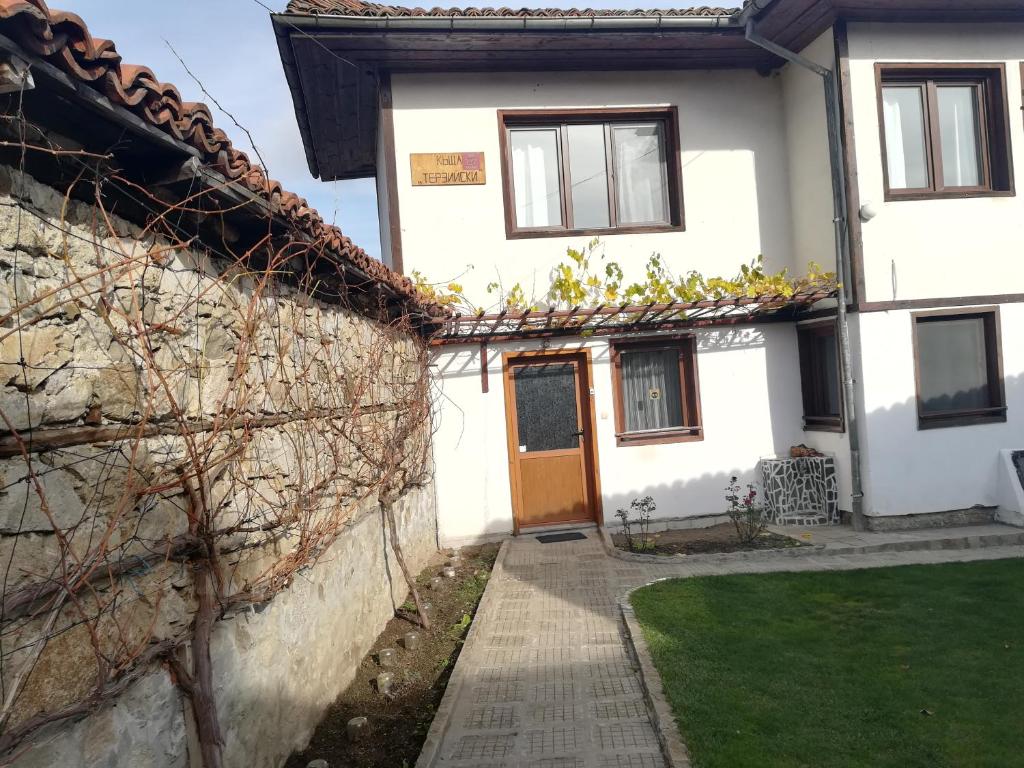 a white house with a door and a yard at Guest House Terziiski in Koprivshtitsa