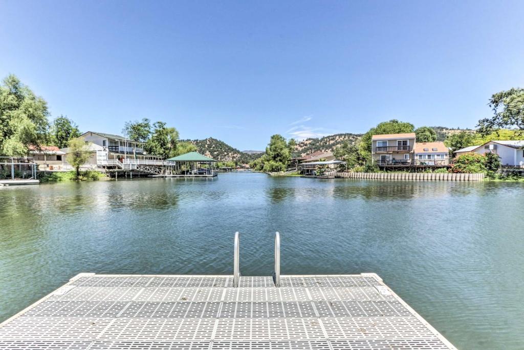 a dock in the middle of a river with houses at Wine Country Oasis with Waterfront Terrace and Dock! in Clearlake Oaks