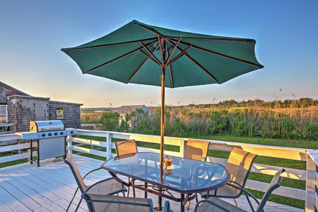 a table and chairs with an umbrella on a deck at Quaint Coastal Cottage with Patio! in Charlestown