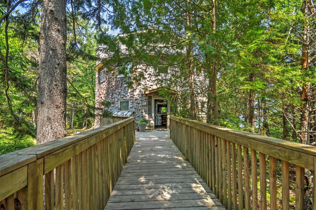 a wooden bridge leading to a stone house in the woods at Dragonwood Castle on Waterfront with Stunning View in Prospect Harbor