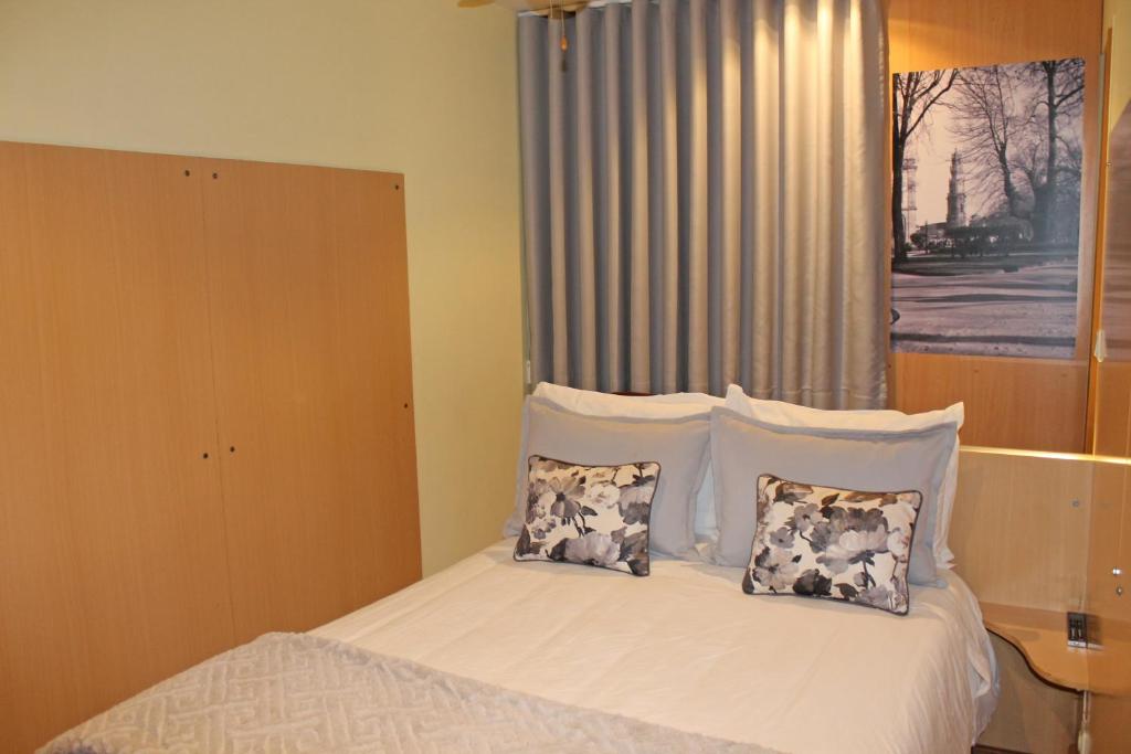 a bed with a white comforter and pillows at Residencial Paranhos in Porto
