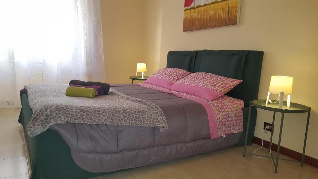 1 dormitorio con 1 cama con almohadas rosas y moradas en Uso Turistico vicino San Giovanni en Roma