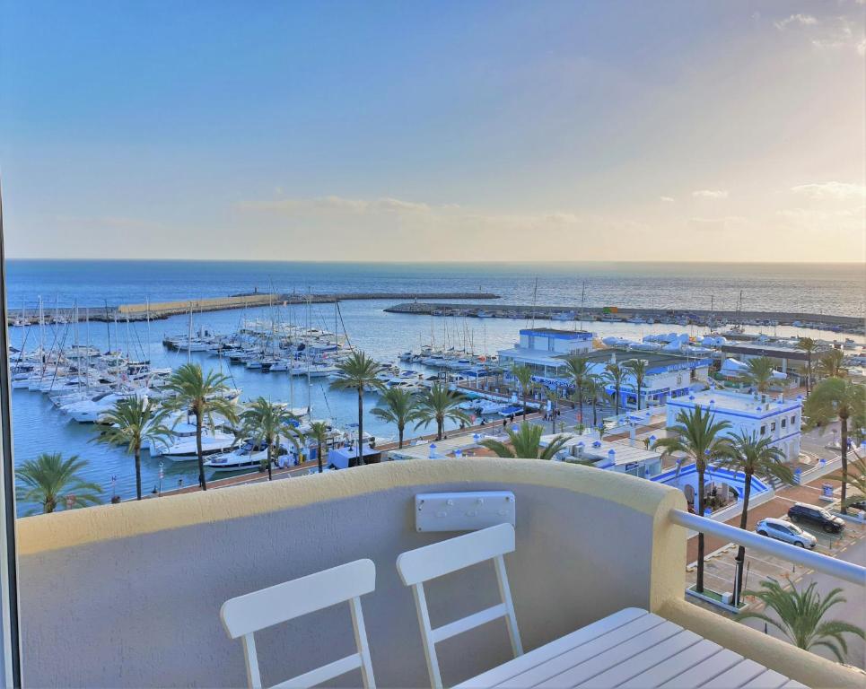 uma varanda com duas cadeiras e uma marina com barcos em FABULOUS APARTMENT IN FRONT OF SEA & MARINA WITH INCREDIBLE VIEWS em Estepona