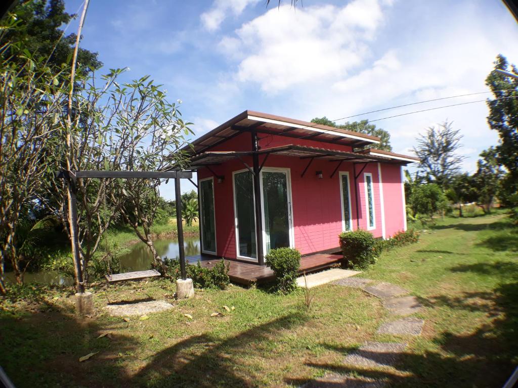 una pequeña casa rosa en medio de un campo en Sawan Srang Nang Kaew, en Takhop