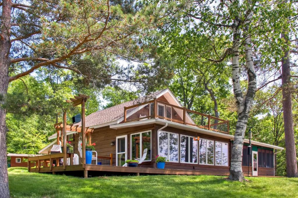 a house with a wrap around porch with trees at Spacious Brainerd Home by Dwtn - Summer Paradise! in Brainerd