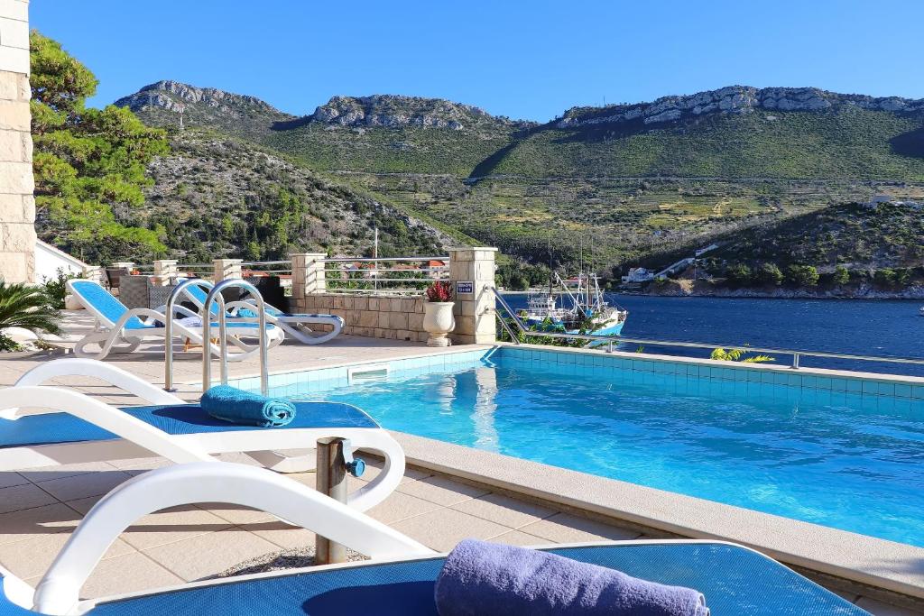 a swimming pool with chairs and a view of the water at Villa Silencia in Trstenik