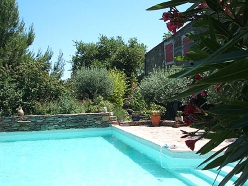 a swimming pool in a garden next to a house at Chambres d'hôtes Sous L'Olivier in Trausse