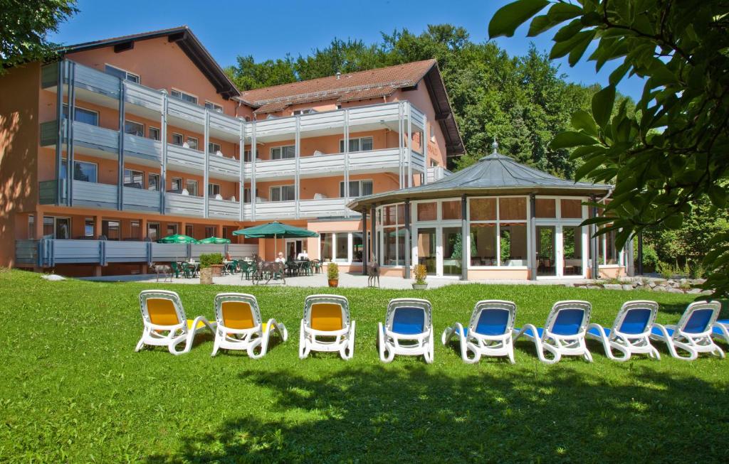 a group of chairs sitting in the grass in front of a building at PTI Hotel Eichwald in Bad Wörishofen