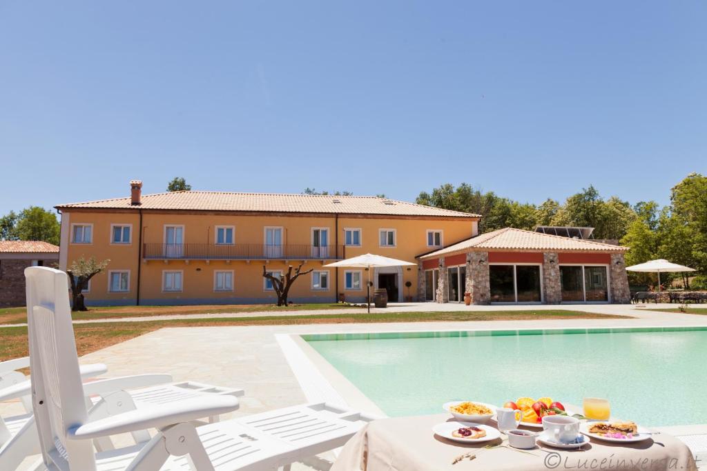 Villa con piscina y mesa con comida. en Agriturismo Creta Rossa, en Torre di Ruggiero