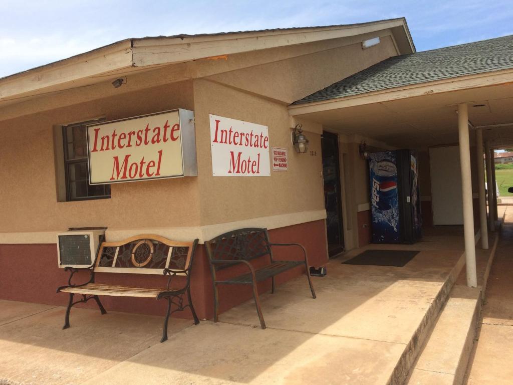 a building with two chairs and signs on the side of it at Interstate Motel in Guthrie