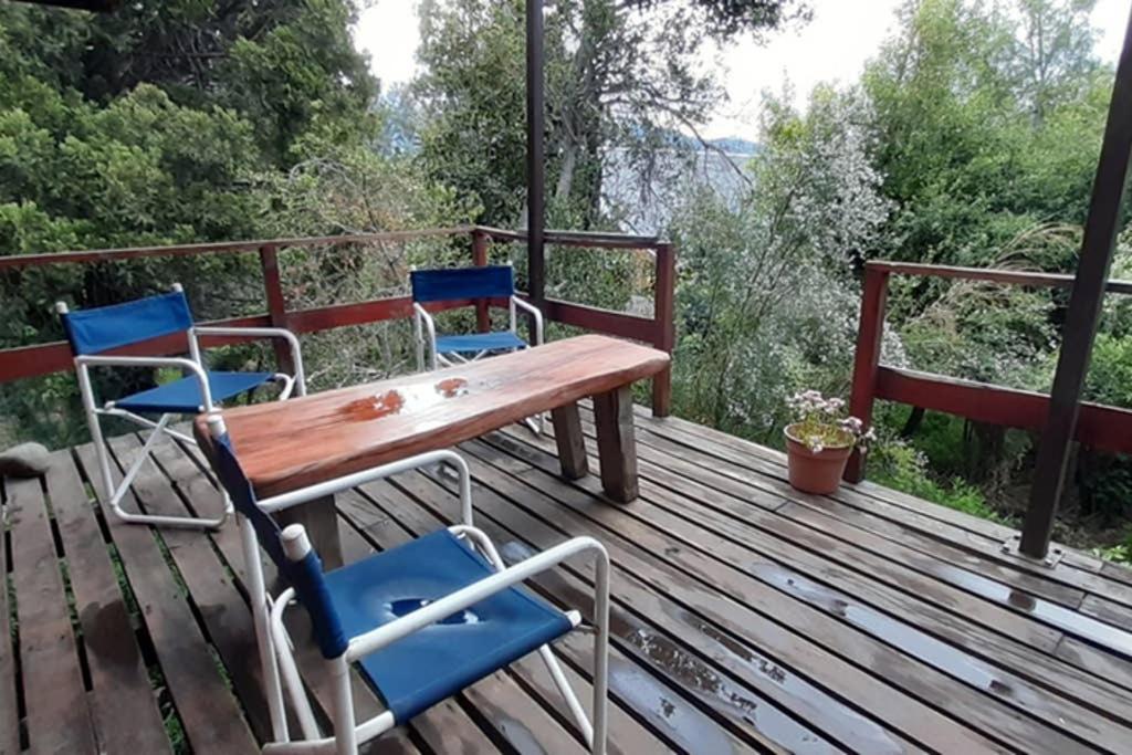 una mesa de madera y sillas en una terraza de madera en Cabaña de montaña en Bosque Nativo en San Carlos de Bariloche