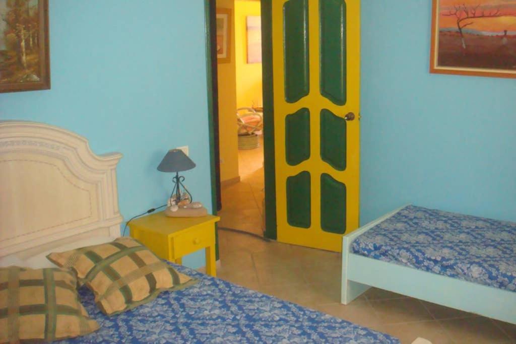 - une chambre avec 2 lits et une porte jaune dans l'établissement Kasa Mona, à Calheta Do Maio