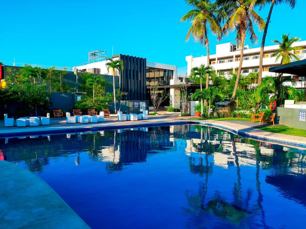 a swimming pool with palm trees and a building at Hotel San Antonio in Tampico