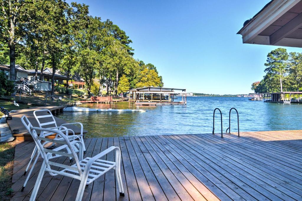 two white chairs sitting on a dock next to the water at Cozy Lake Cabin with Dock in Hot Springs Natl Park in Lake Hamilton