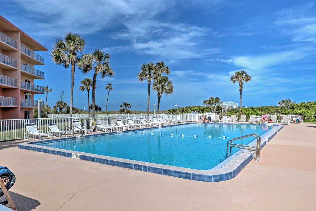 uma piscina num resort com cadeiras e palmeiras em Oceanfront Cocoa Beach Condo with View Walk to Pier em Cocoa Beach