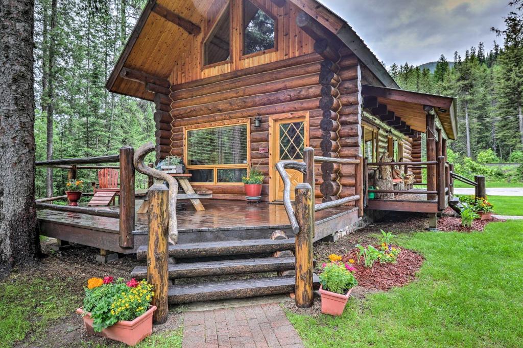 Cabaña de madera en el bosque con porche y escaleras en Cozy Glacier Park Log Cabin - Best in the West! en Essex