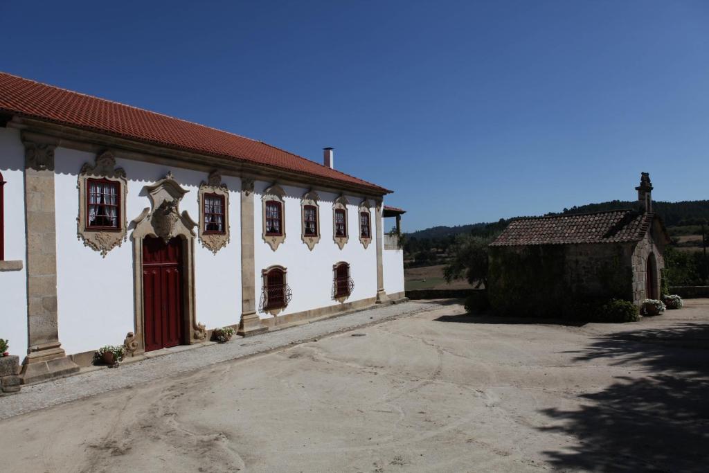 a white building with a red door and a church at Casa de Darei in Mangualde